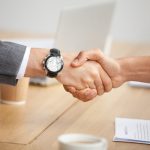 Close up view of handshake, two businessmen in suits shaking hands as concept of trust, good partnership deal, signing contract agreement at meeting, gratitude for help support in business
